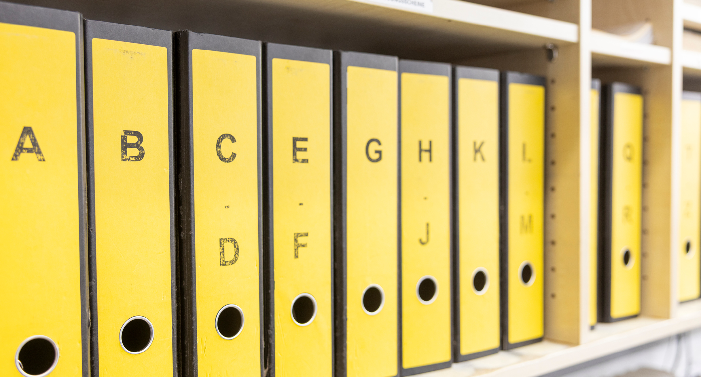 Gelbe Ordner nach Alphabet sortiert stehen im Regal